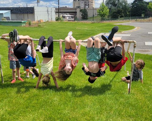 A CoreFit member holds a plank position. Owner Kurt kneels with arm outstretched to offer posture guidance.